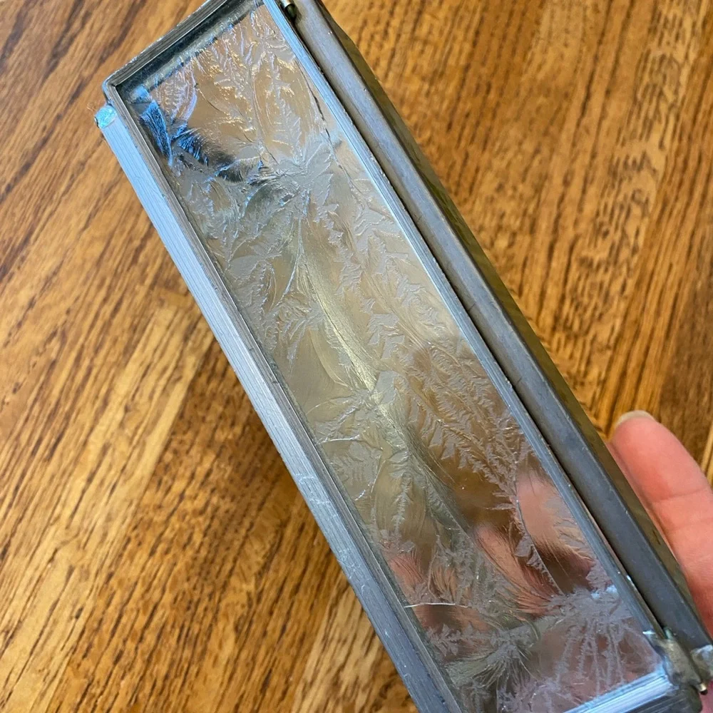 Small, heavy glass box with pressed flowers on top and mirrored bottom